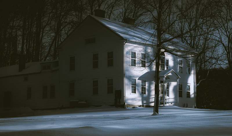 Dimly lit paranormal investigation lab with EMF meter, spirit box, and flickering monitor showing static